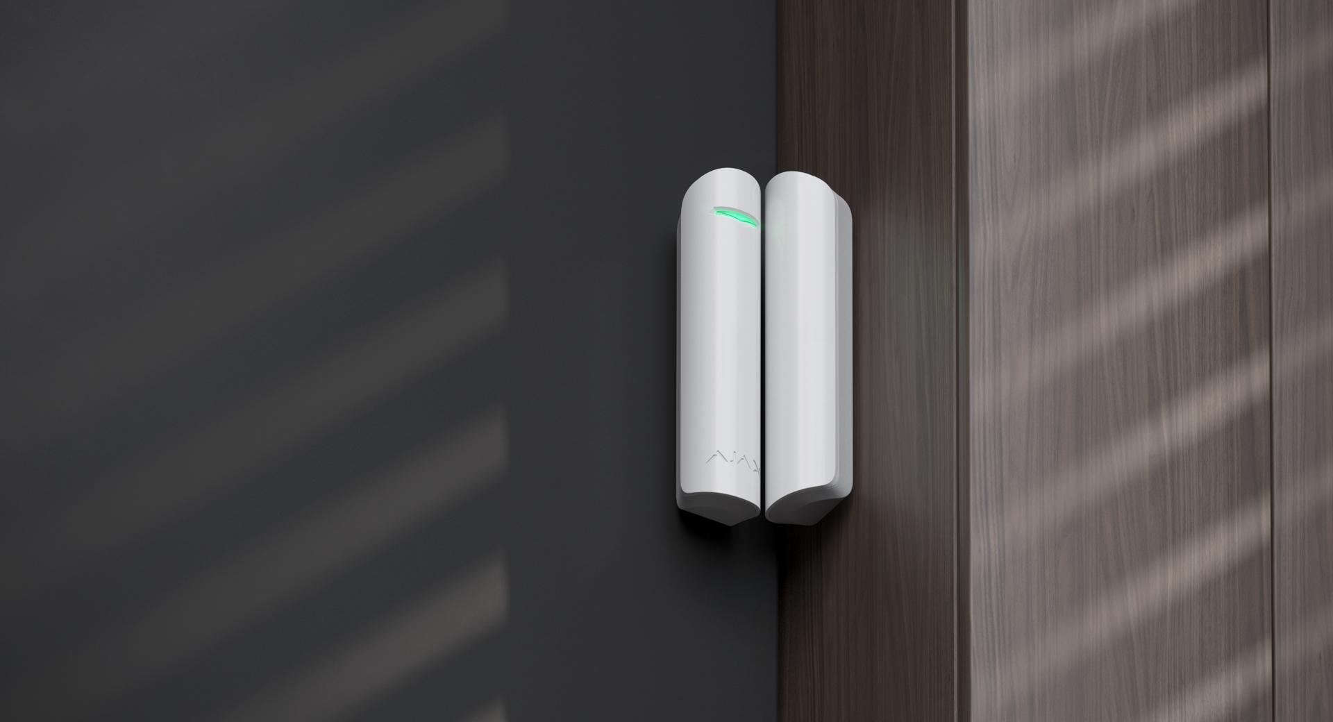 An Ajax DoorProtect wireless door sensor in white on a home entry door