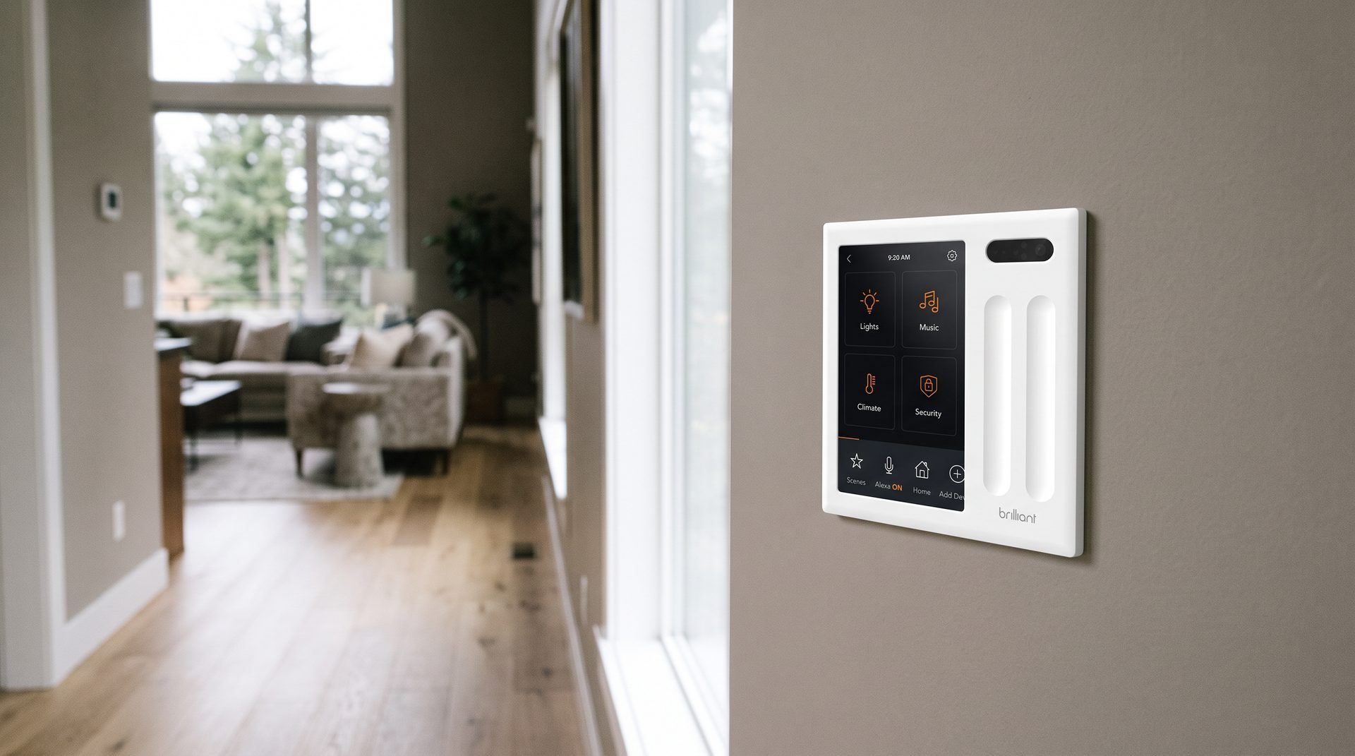 A Brilliant in-wall control panel with its touchscreen and two slider bars in a Pacific Northwest hallway, living room beyond