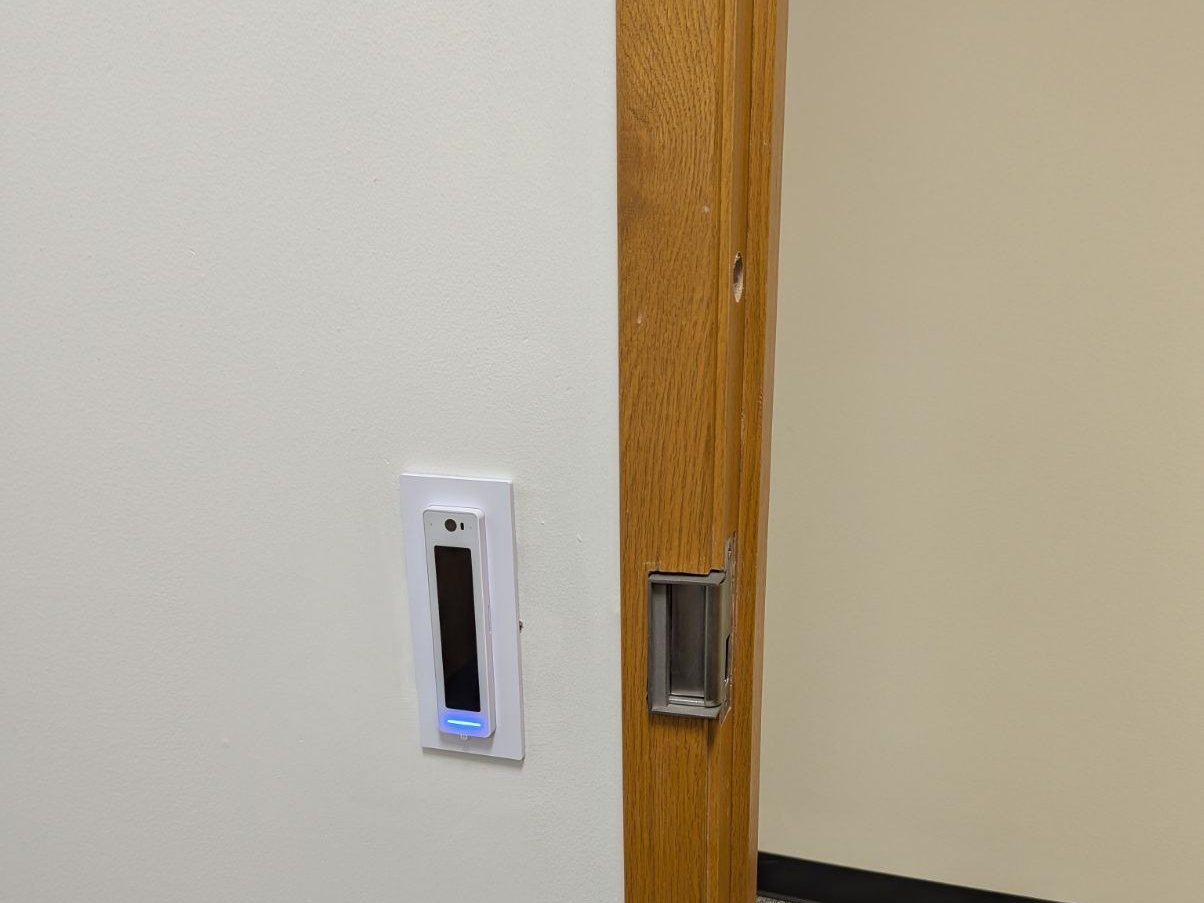 The UniFi Access touchscreen reader installed beside the main entrance door of the Bellevue office suite