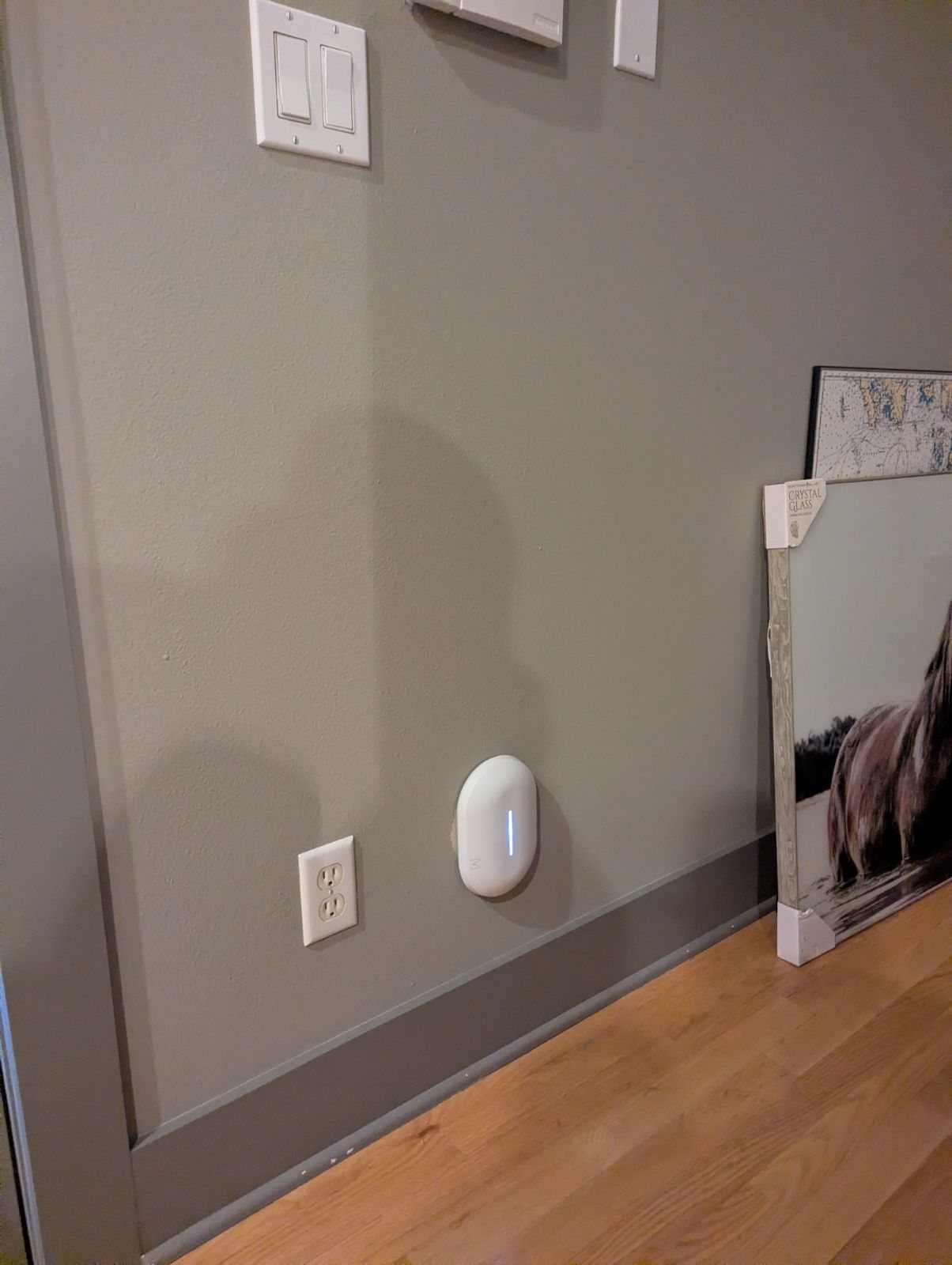 An Alta Labs Summit-A6 access point mounted low on a gray hallway wall beside an outlet