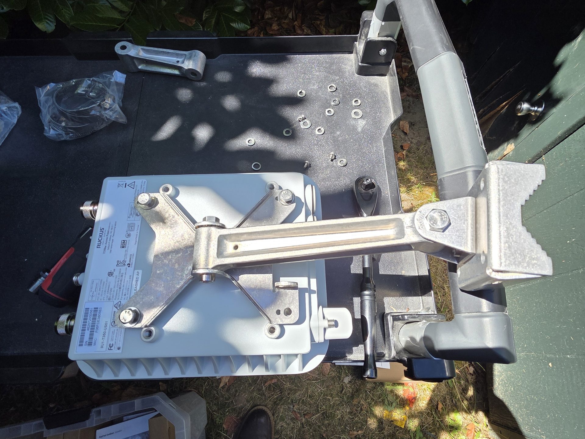 A Ruckus outdoor access point on its articulating pole-mount bracket on the work bench