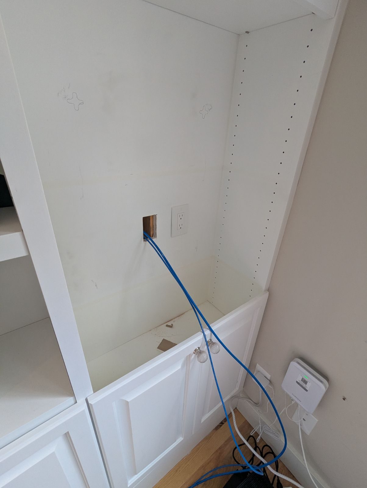 New blue Cat6 cables coming through the back of a built-in shelf where the network rack would mount