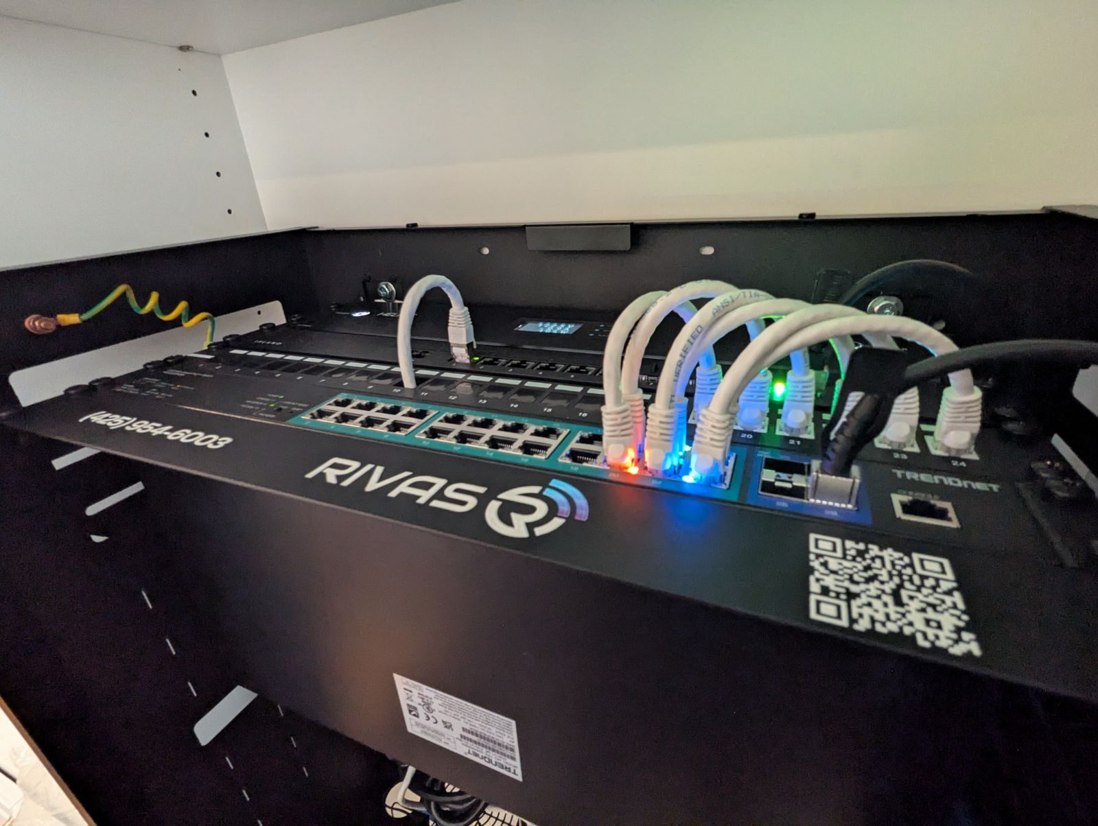 The Island Router Pro and the TRENDnet 2.5G PoE++ switch in the open wall rack, with short white patch cables