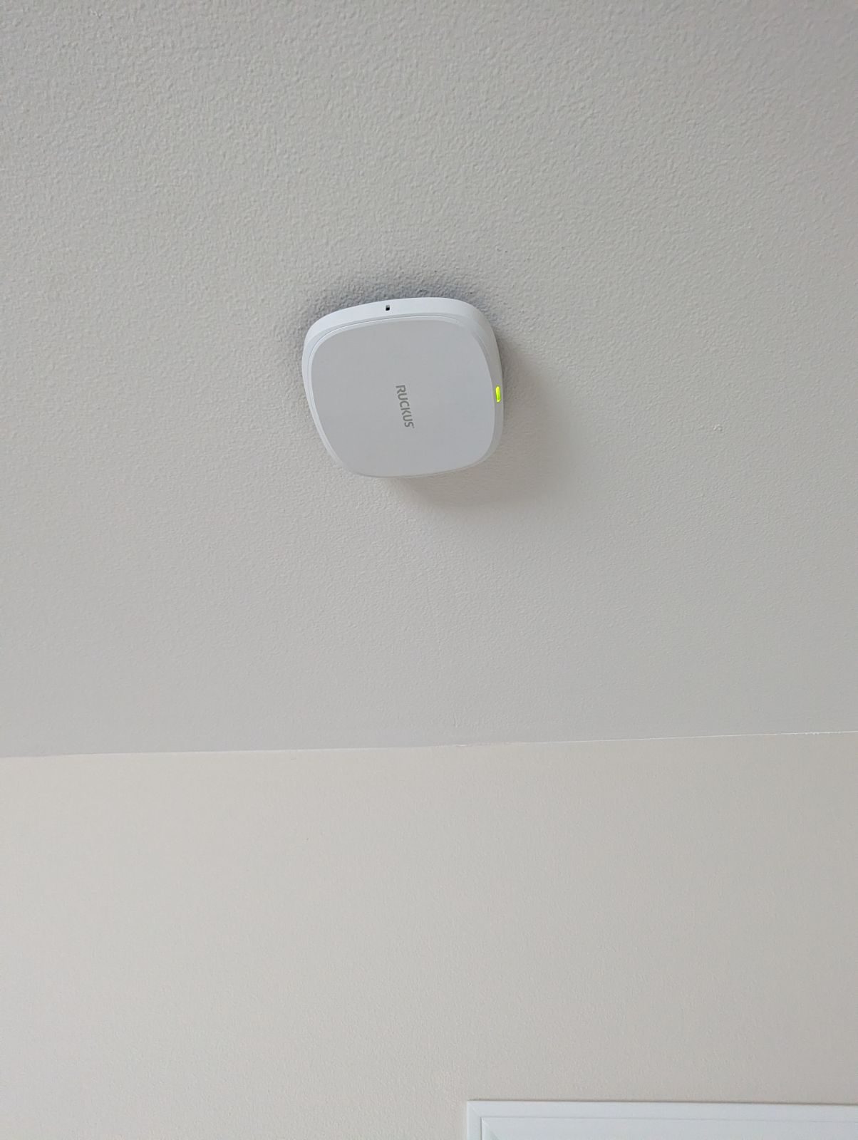 A white Ruckus R370 Wi-Fi 7 access point on a textured ceiling